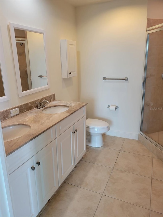 bathroom with double vanity, a shower stall, a sink, and tile patterned floors