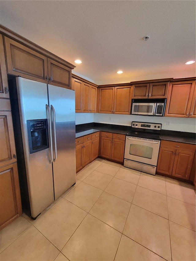 kitchen with dark countertops, light tile patterned floors, appliances with stainless steel finishes, and recessed lighting