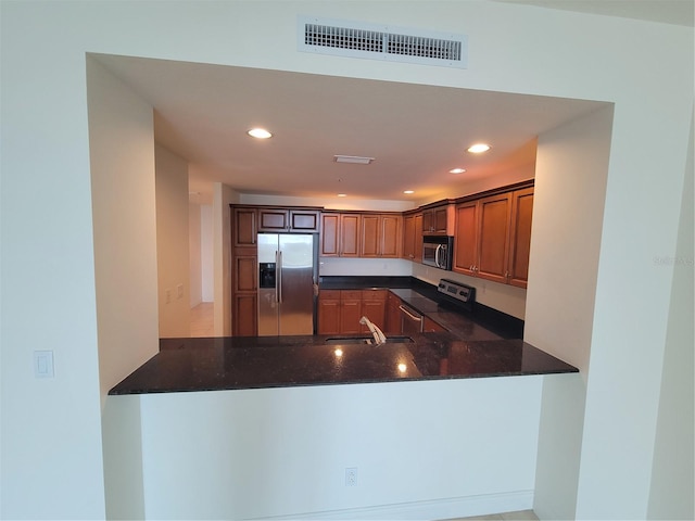 kitchen with dark stone counters, a peninsula, appliances with stainless steel finishes, and visible vents