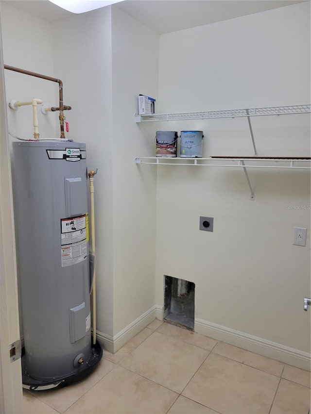 clothes washing area featuring light tile patterned floors, water heater, electric dryer hookup, laundry area, and baseboards