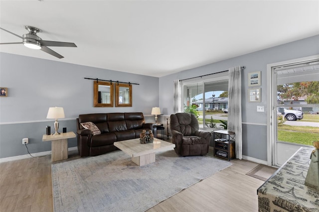 living room featuring ceiling fan, baseboards, and wood finished floors