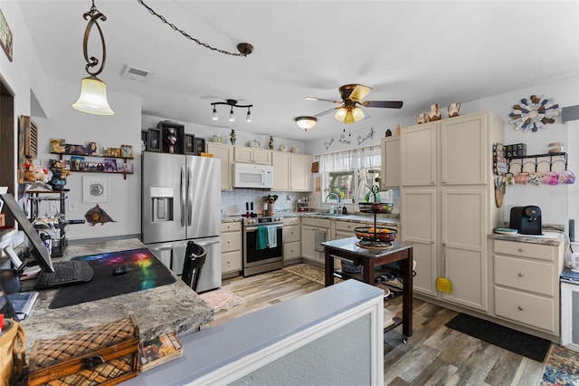 kitchen with a sink, tasteful backsplash, appliances with stainless steel finishes, light wood finished floors, and ceiling fan