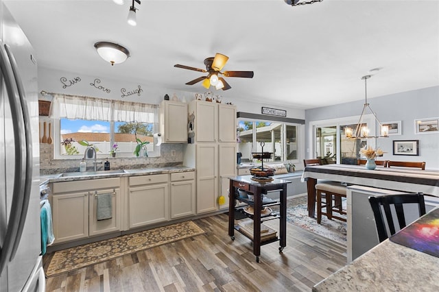 kitchen with pendant lighting, a sink, tasteful backsplash, wood finished floors, and freestanding refrigerator