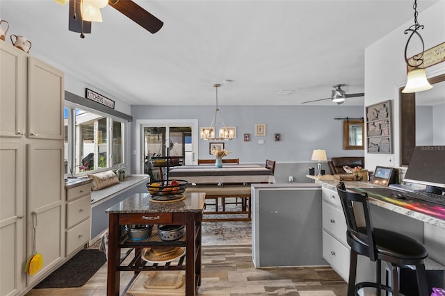 kitchen with decorative light fixtures, ceiling fan with notable chandelier, and light wood finished floors