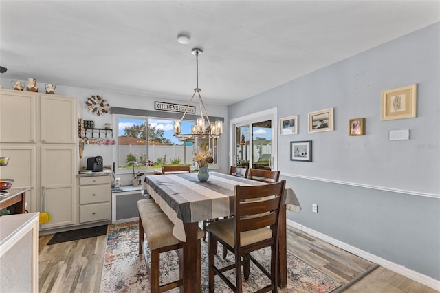 dining room with light wood-style floors, baseboards, and a chandelier