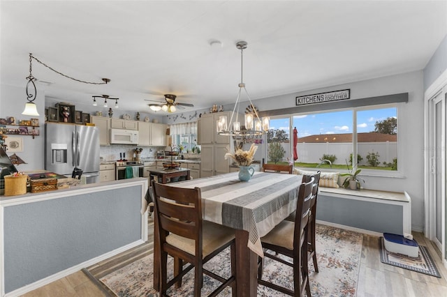 dining room featuring ceiling fan with notable chandelier and light wood-type flooring