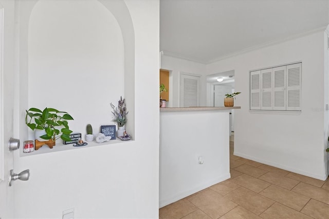 spare room with arched walkways, light tile patterned flooring, crown molding, and baseboards