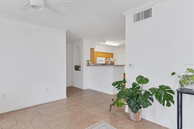 interior space featuring light tile patterned floors, visible vents, ornamental molding, ceiling fan, and baseboards