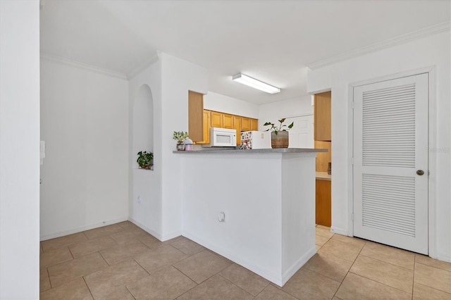 kitchen featuring ornamental molding, arched walkways, white appliances, and light tile patterned flooring