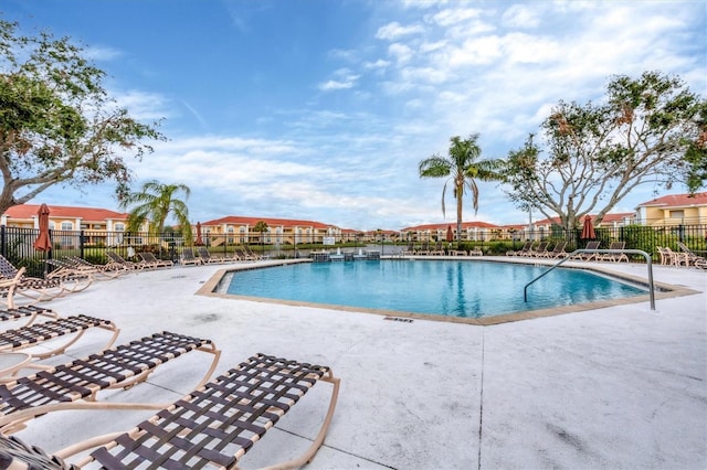 community pool featuring a patio area, fence, and a residential view