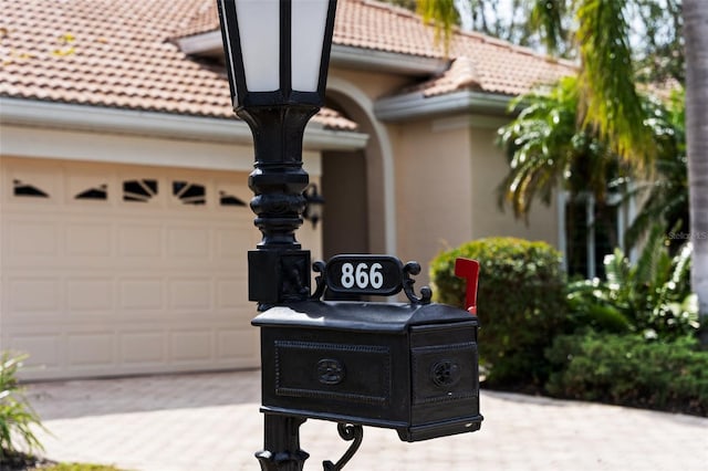 exterior details with a tiled roof, driveway, and stucco siding