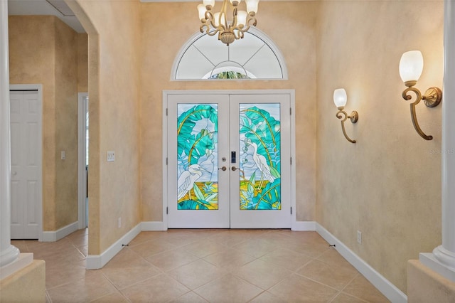 tiled entrance foyer with baseboards, decorative columns, arched walkways, and french doors