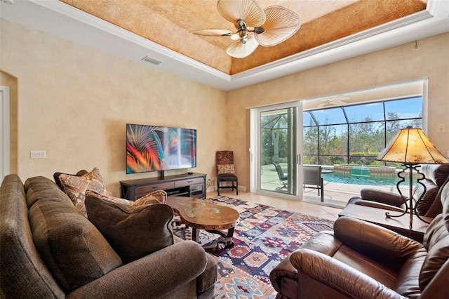 tiled living room featuring a tray ceiling, visible vents, a ceiling fan, a sunroom, and baseboards