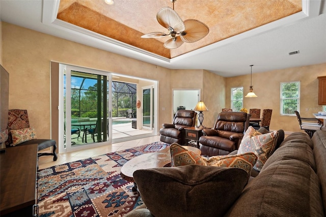 living room with light tile patterned floors, ceiling fan, a raised ceiling, and visible vents