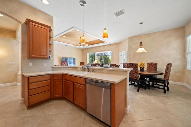 kitchen featuring light countertops, a sink, a peninsula, and stainless steel dishwasher