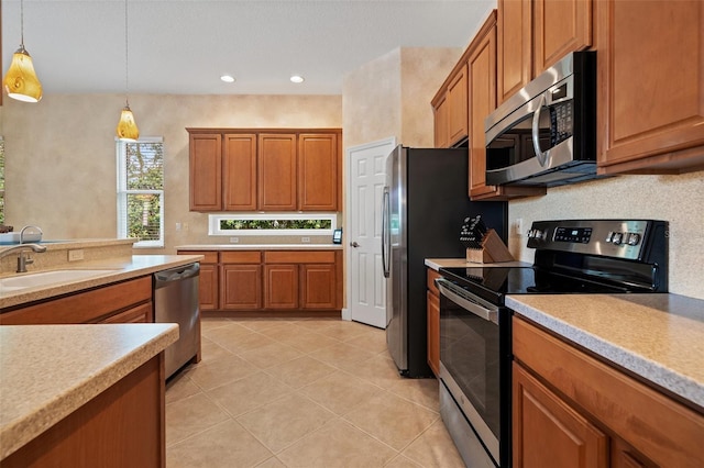 kitchen with brown cabinetry, stainless steel appliances, a sink, and light countertops