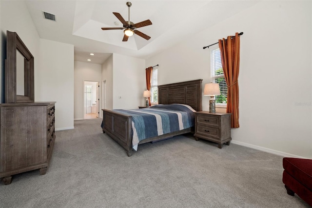 bedroom with a tray ceiling, light carpet, baseboards, and recessed lighting