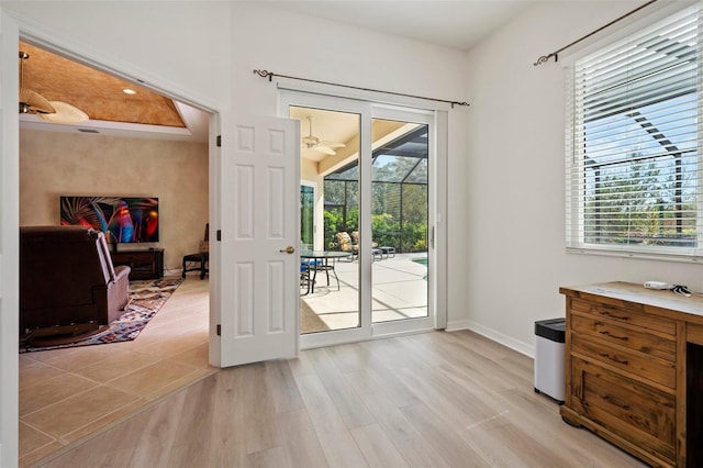 doorway to outside with baseboards, ceiling fan, light wood-style floors, and a healthy amount of sunlight