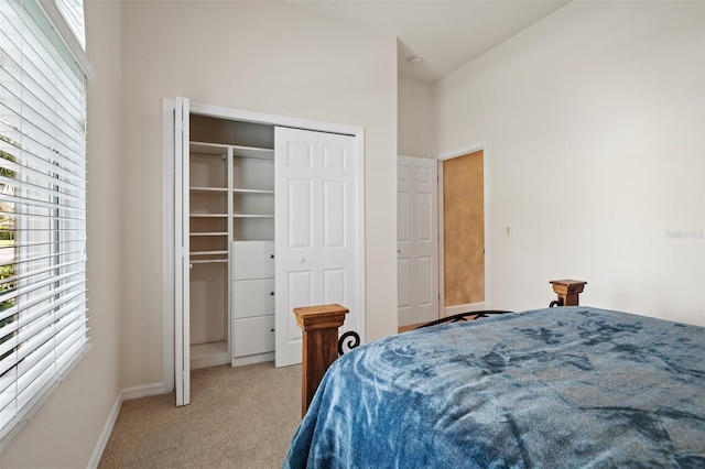 bedroom featuring a closet, light colored carpet, and baseboards