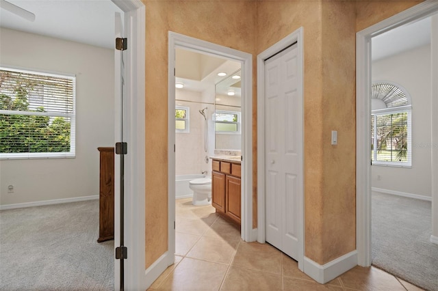 hall featuring light carpet, light tile patterned floors, and baseboards