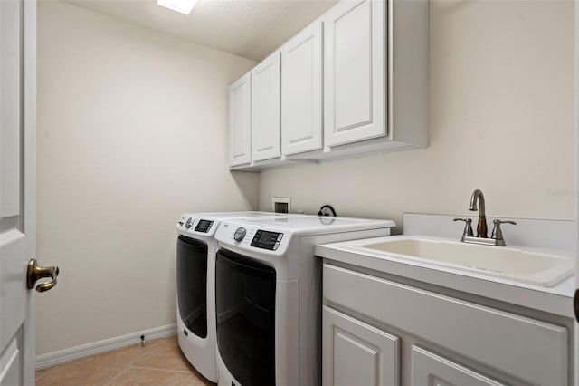 clothes washing area featuring cabinet space, light tile patterned flooring, a sink, separate washer and dryer, and baseboards