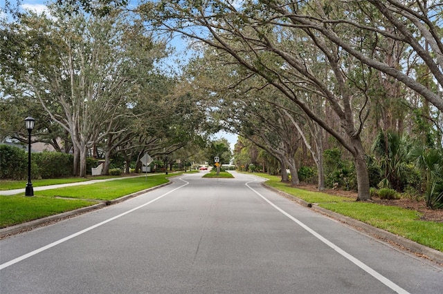 view of road featuring traffic signs, street lighting, and curbs