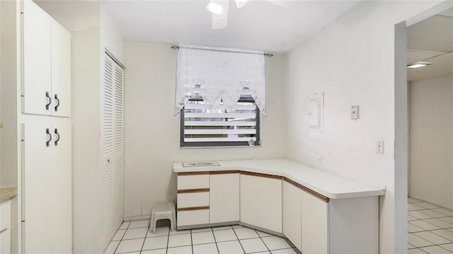 interior space with light tile patterned floors, ceiling fan, and white cabinets