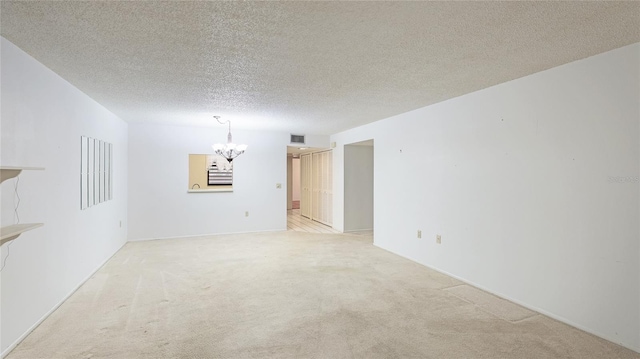 unfurnished room with a chandelier, light carpet, visible vents, and a textured ceiling