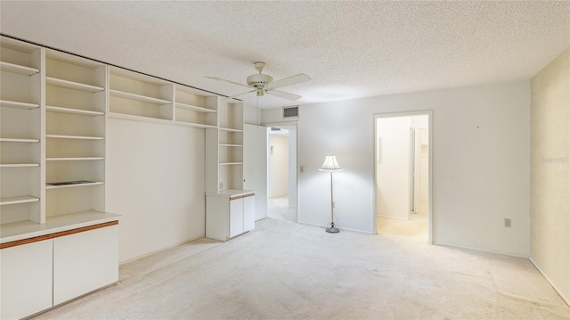 unfurnished bedroom featuring ceiling fan, visible vents, a textured ceiling, and light colored carpet