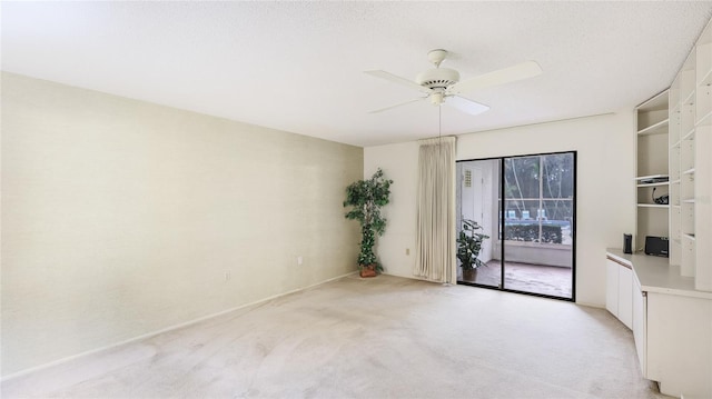 empty room featuring ceiling fan, a textured ceiling, and light colored carpet