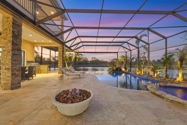 pool at dusk featuring a patio, area for grilling, a pool with connected hot tub, and a lanai