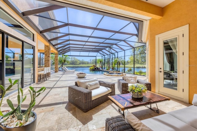 view of patio / terrace with a lanai, a water view, and an outdoor living space