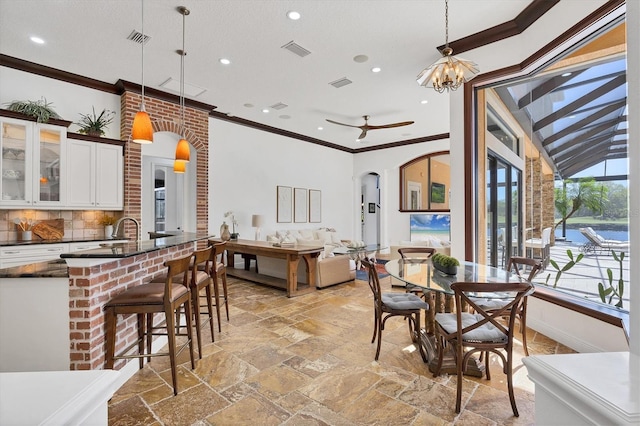 dining space featuring arched walkways, visible vents, ornamental molding, and stone tile flooring