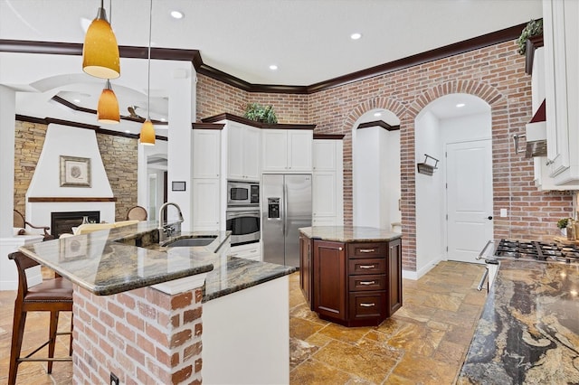 kitchen featuring a large island, a sink, dark stone countertops, appliances with stainless steel finishes, and a fireplace