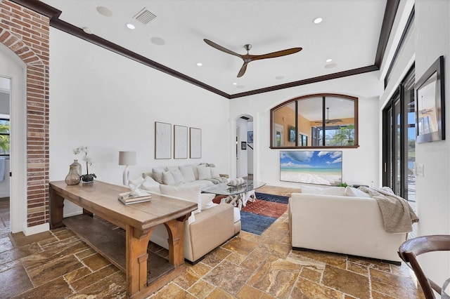 living room featuring stone tile flooring, visible vents, arched walkways, and ornamental molding