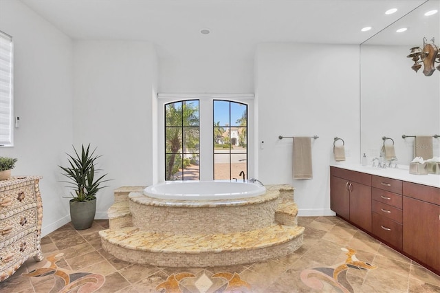 bathroom featuring baseboards, recessed lighting, vanity, and a garden tub