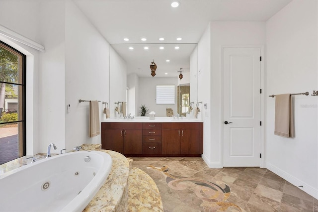 full bath with baseboards, double vanity, recessed lighting, a sink, and a jetted tub