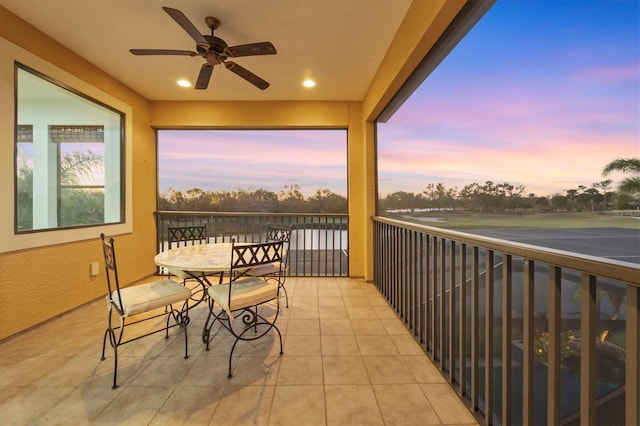 balcony at dusk featuring ceiling fan