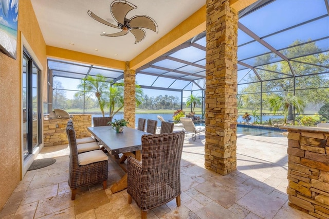 exterior space featuring a water view, a ceiling fan, an outdoor kitchen, outdoor dining area, and a lanai