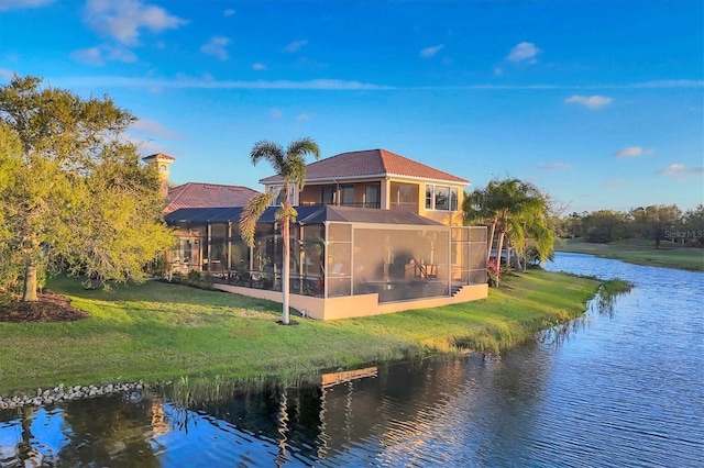 back of property featuring a lawn, a water view, and a sunroom