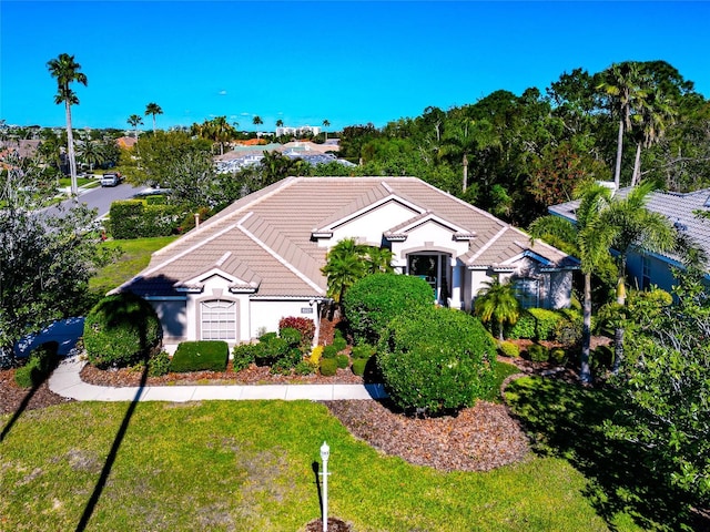 view of front of house with stucco siding, a front lawn, and a tile roof