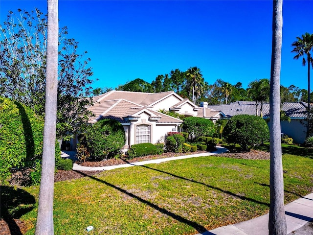 view of front facade with stucco siding, a front lawn, and a tiled roof