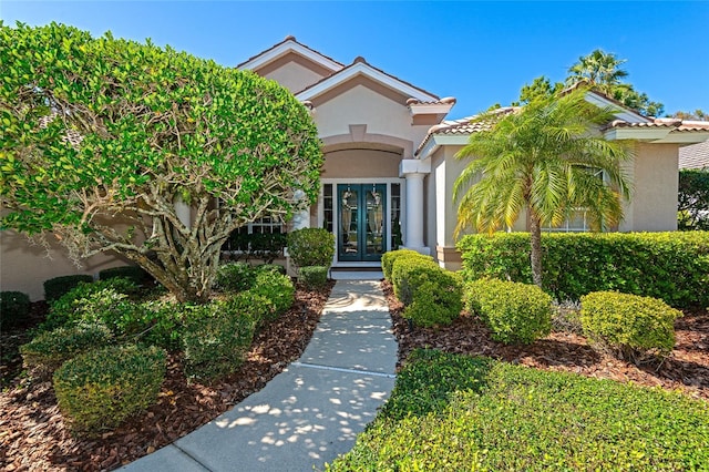 entrance to property featuring french doors, stucco siding, and a tile roof