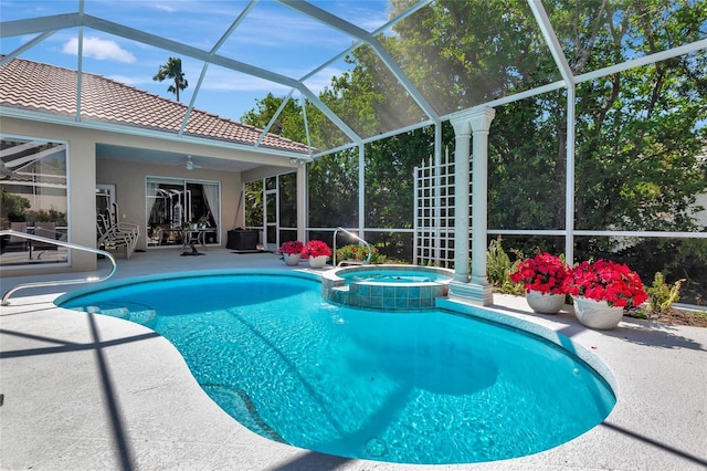 view of pool with glass enclosure, a patio area, a pool with connected hot tub, and ceiling fan