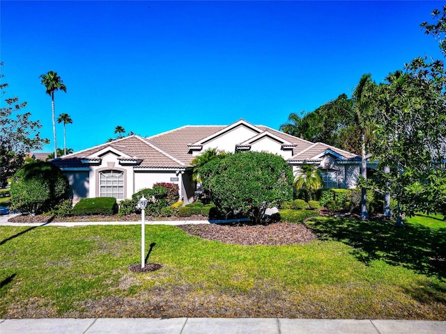 view of front facade with stucco siding, a tile roof, and a front lawn