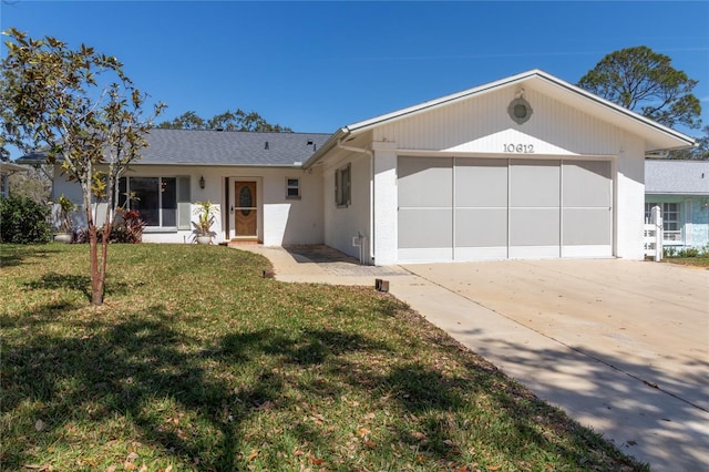 ranch-style home with a shingled roof, concrete driveway, an attached garage, a front lawn, and stucco siding