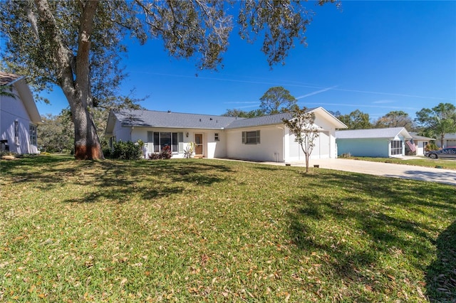 ranch-style house with driveway, an attached garage, a front lawn, and stucco siding