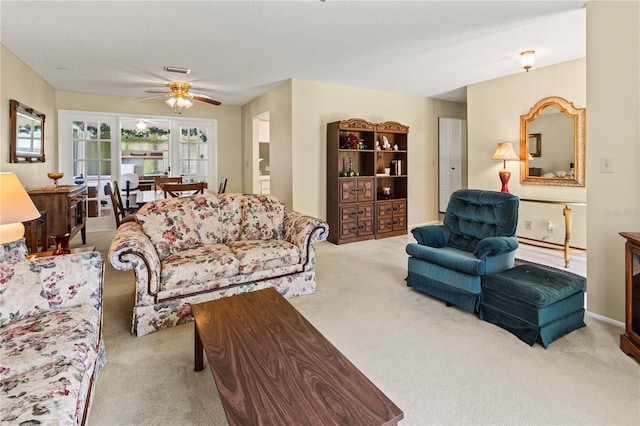 living room featuring carpet, a textured ceiling, visible vents, and a ceiling fan