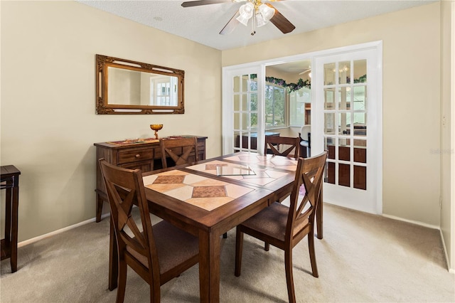 dining area featuring light carpet, ceiling fan, and baseboards