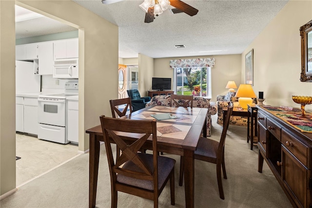 dining area featuring visible vents, light colored carpet, ceiling fan, and a textured ceiling